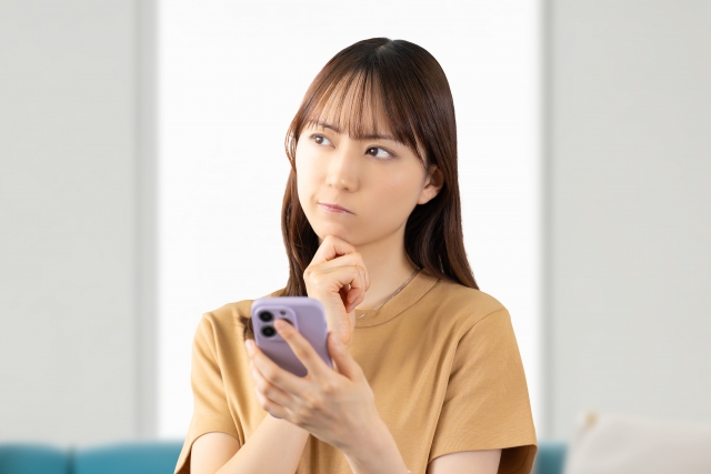 スマホを手に悩む女性